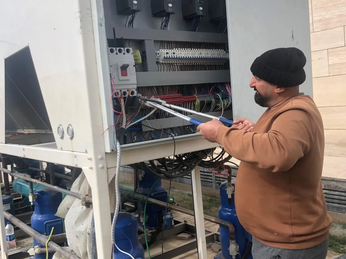 Bakım ziyaretinde chiller elektrik panosunda ölçüm yapan teknisyen
